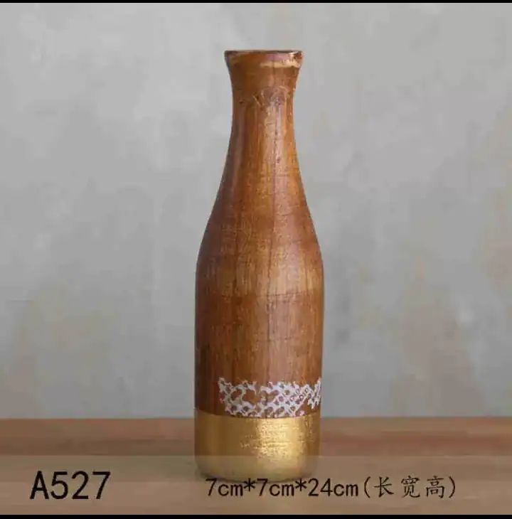 فازة ديكور خشبية طويلة بتصميم أسطواني ولون بني طبيعي مزينة بنقوش بيضاء وقاعدة ذهبية لامعة بمقاس 24 سم.