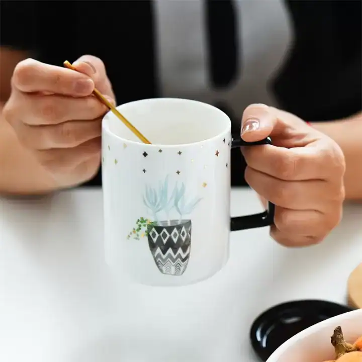 كوب قهوة سيراميك أبيض للمكتب مع غطاء أسود ورسمة نبتة