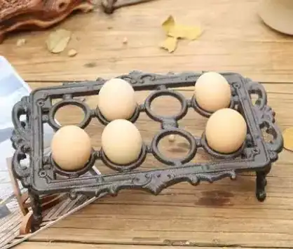 حامل بيض معدني مستطيل باللون البرونزي العتيق يضم 8 بيضات موضوع على طاولة خشبية بتصميم ريفي كلاسيكي