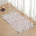 دعاسات قماشية مودرن باللون الرمادي المزرق مع أهداب بيج موضوعة بجانب سرير في غرفة نوم عصرية بتصميم هادئ