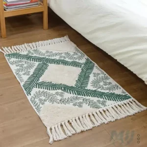 دعاسة باب قماشية بنقشة أوراق شجر خضراء وخلفية كريمية مع أهداب جانبية موضوعة بجانب سرير في غرفة نوم عصرية