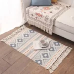 سجاد الباب قماشي بنقوش هندسية ملونة بالأزرق والوردي مع أهداب جانبية ناعمة موضوع في زاوية جلوس بجانب أريكة عصرية