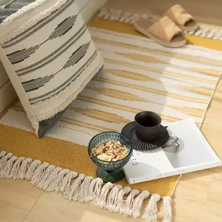 دعاسة مدخل قماشية مخططة باللون الأصفر الخردلي والأبيض مع أهداب جانبية موضوعة في زاوية استرخاء عصرية مع مخدة ديكور