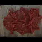 شبك من الخيش السميك الملون باللون البني القرميدي والبرتقالي يستخدم كطبقة خلفية ريفية وبساط بوهيمي لتصوير المواليد حديثي الولادة