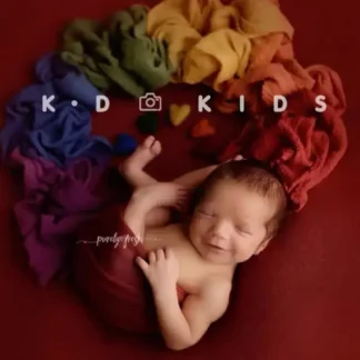 طفل مولود ملفوف بقماش ستريتش احمر ومحاط بلفات ملونة تشكل قوس قزح