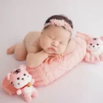 مخدة صوف حجم كبير بتصميم محبوك باللون الوردي والسماوي والرمادي تستخدم كقاعدة دعم مريحة لتصوير المواليد حديثي الولادة