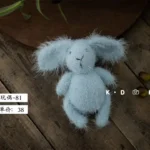 دمية أرنب من الصوف الناعم بتصميم وبري فلافي وآذان طويلة متوفرة بألوان بيج وأصفر ووردي وسماوي لتصوير المواليد باحترافية