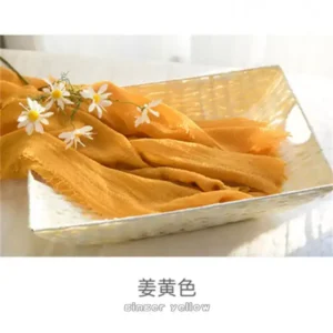 لفة قماش قطن لتصوير المواليد لون أصفر زنجبيلي خردلي داخل سلة مع زهور