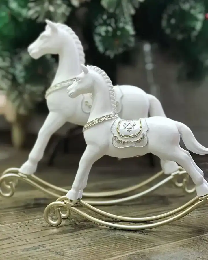 حصان هزاز ديكور صغير الحجم مصنوع من الريزن الأبيض مع سرج وقاعدة منحنية باللون الذهبي بتصميم كلاسيكي فاخر.