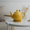 ابريق شاي London Pottery لون اصفر مشرق مع فلتر ستانلس ستيل على طاولة بيضاء