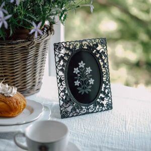 إطار صور معدني اسود بتصميم مفرغ وزخارف نباتية وفتحة بيضاوية